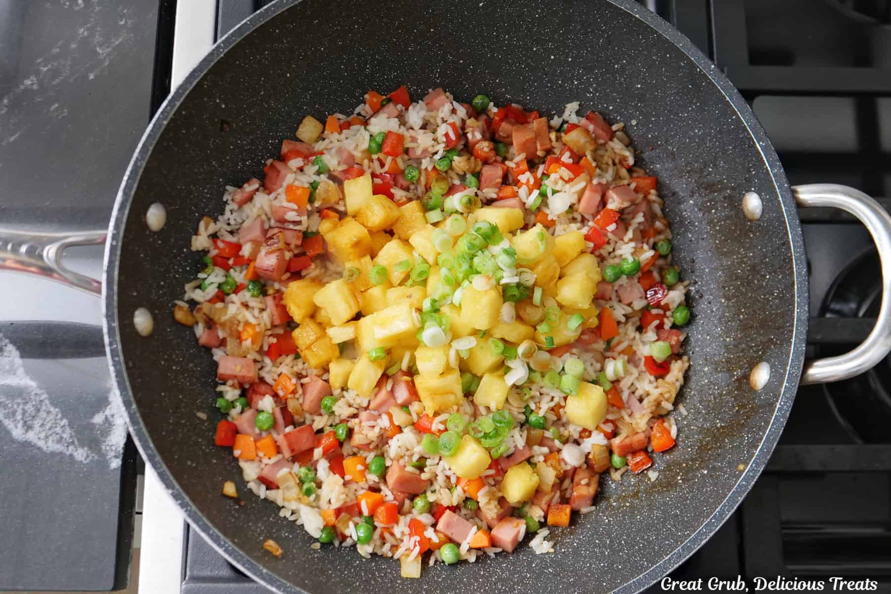 A wok with all the ingredients in it to make Hawaiian fried rice with pineapple and Spam.