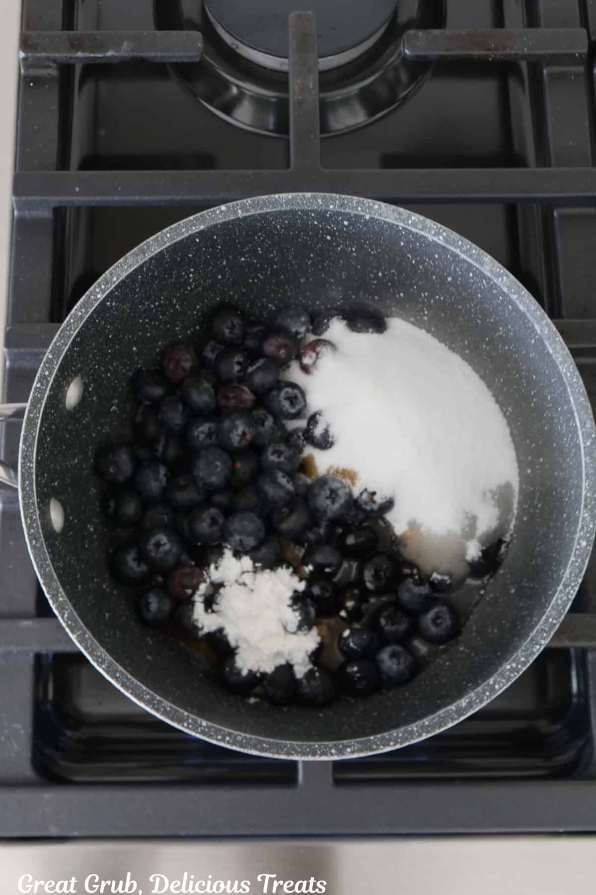 A saucepan with all the ingredients in it to make blueberry sauce.