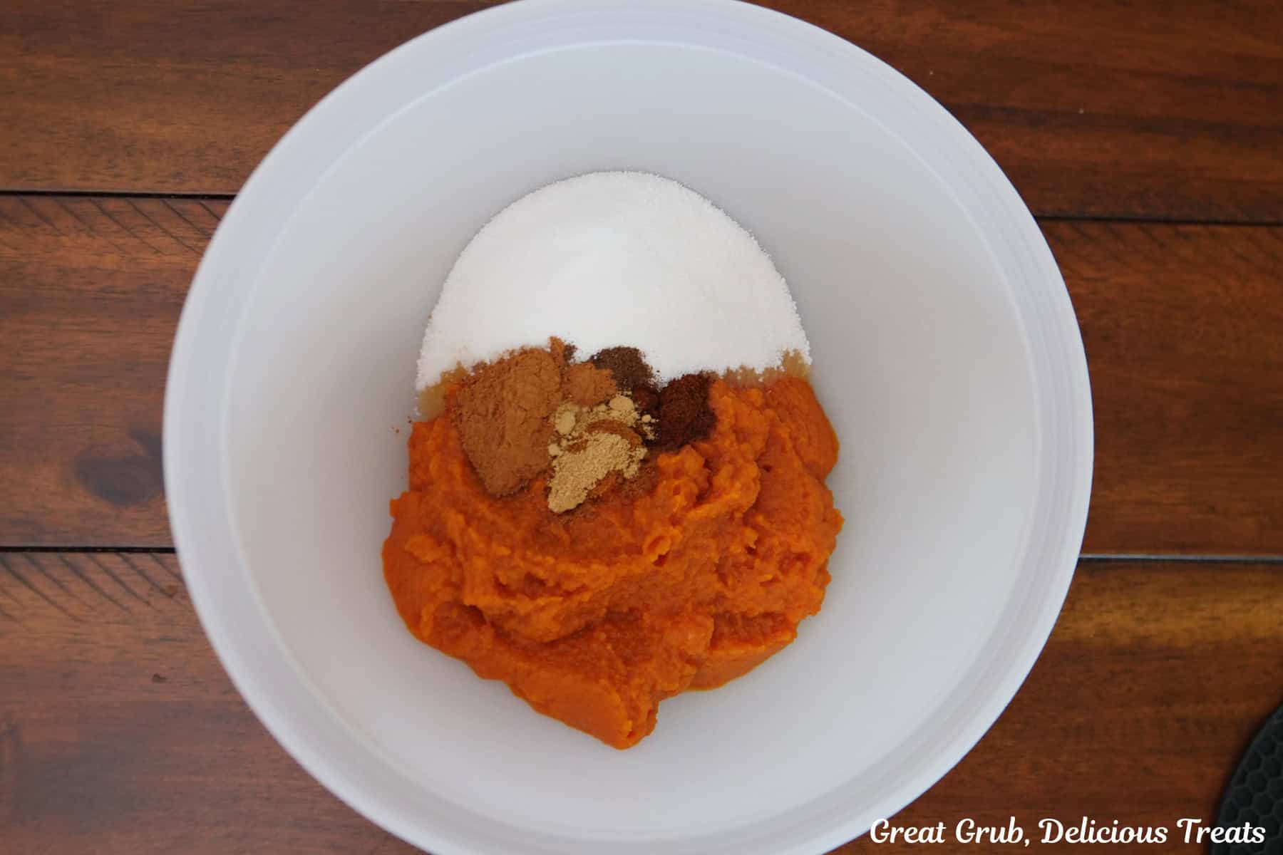 A white mixing bowl with the pumpkin filling ingredients in it before being mixed together.