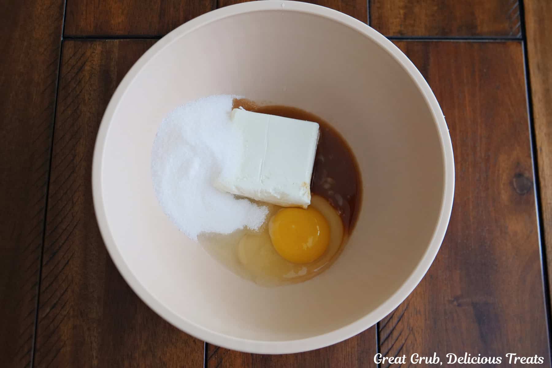 A cream color bowl with the cream cheese mixture ingredients in it before being mixed together,