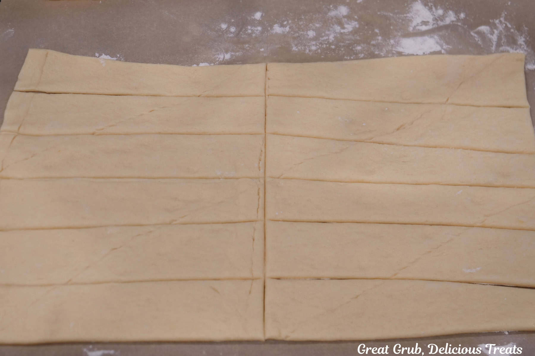 A countertop with crescent dough rolled out and cut into strips.