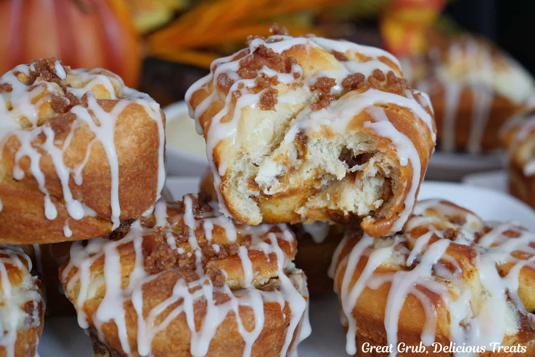 A white plate with six pumpkin muffins on it with a bite taken out of one of the muffins on top.