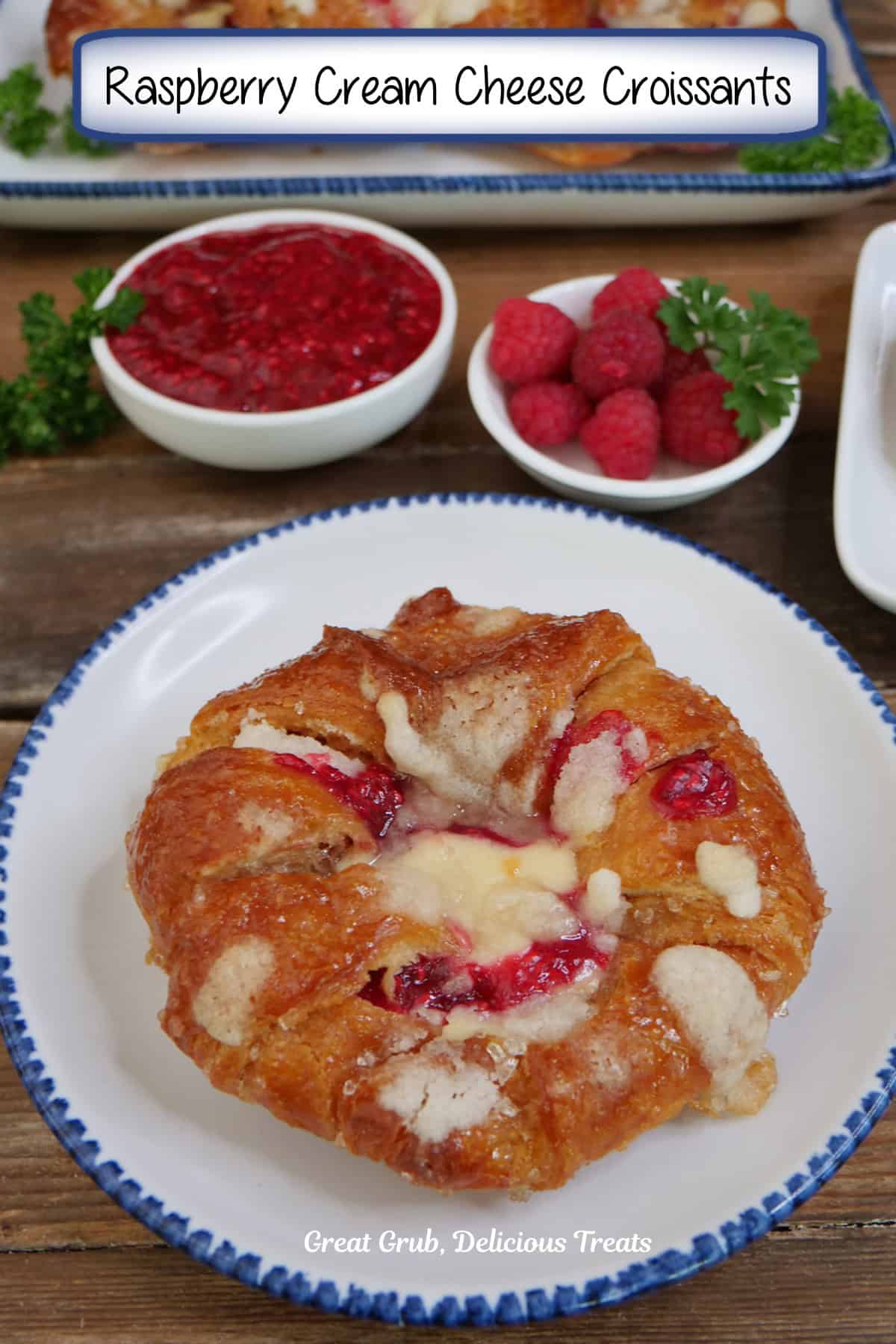 A white plate with blue trim with a round large croissant on it filled with a cheesecake layer and raspberry filling, and a title overlay at the top.
