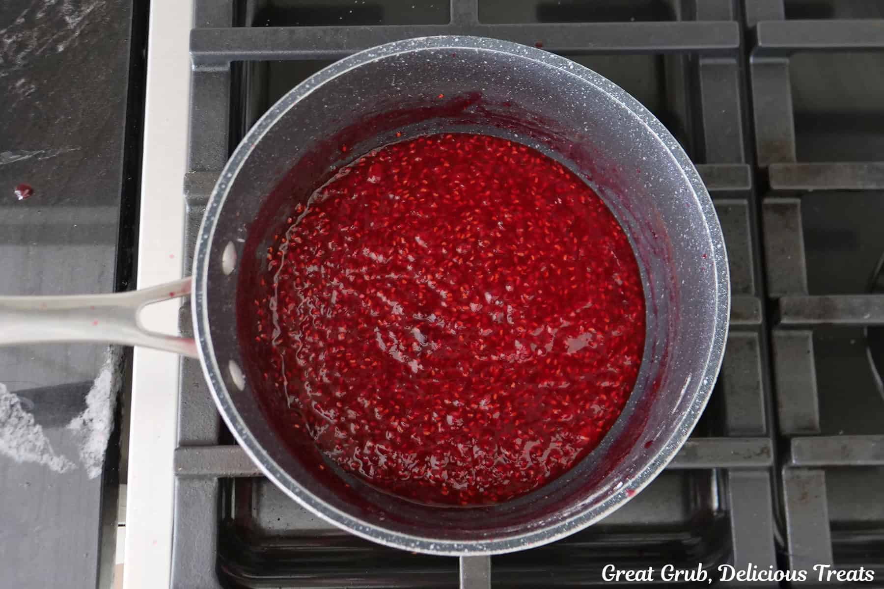 A saucepan on the stovetop with homemade raspberry filling it in.