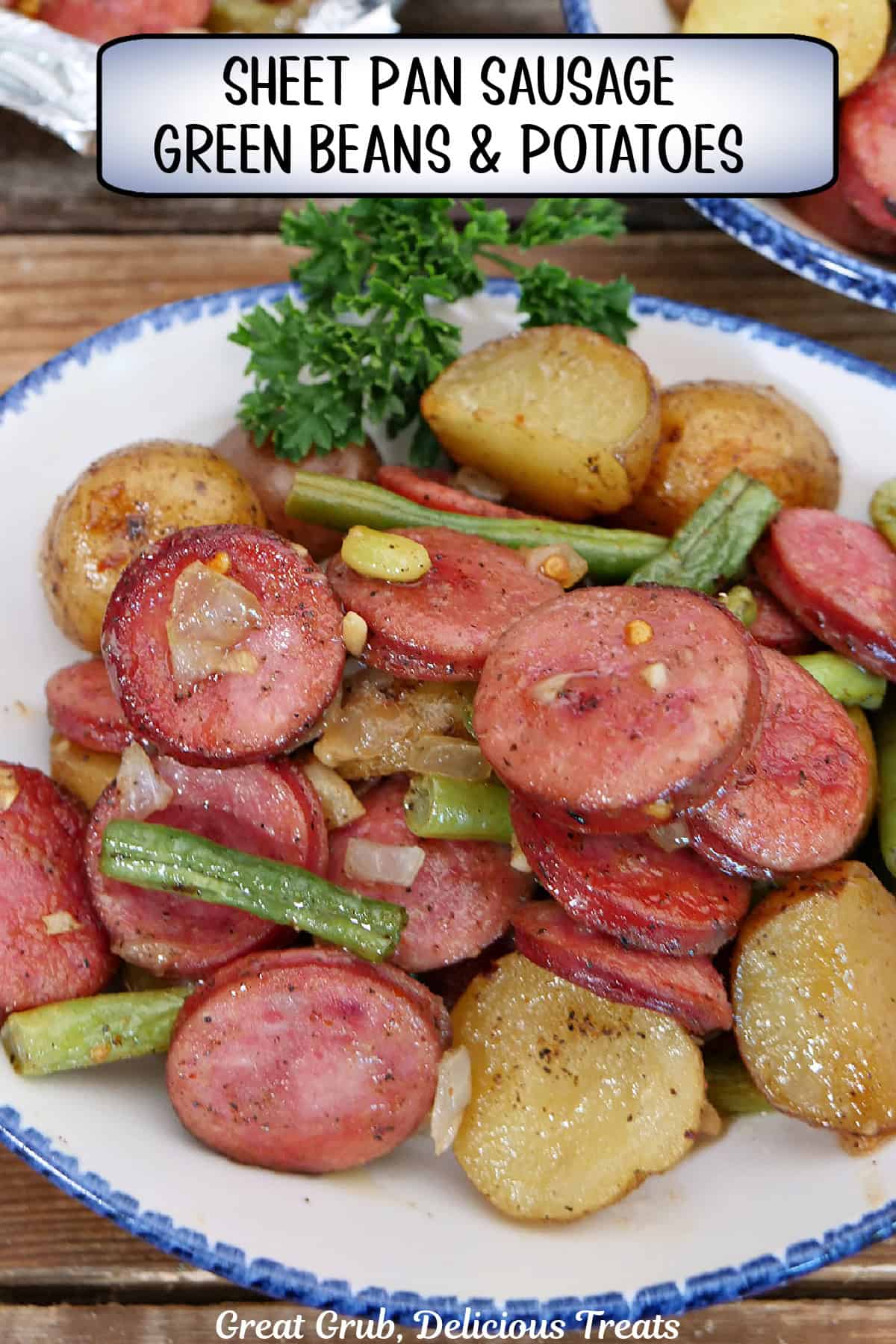 A white bowl with blue trim with a serving of sausage, green beans, and potatoes sheet pan meal in it with a title overlay at the top.