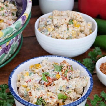 A wood surface with two white bowls filled with a serving of street corn pasta salad, and a title overlay at the top.