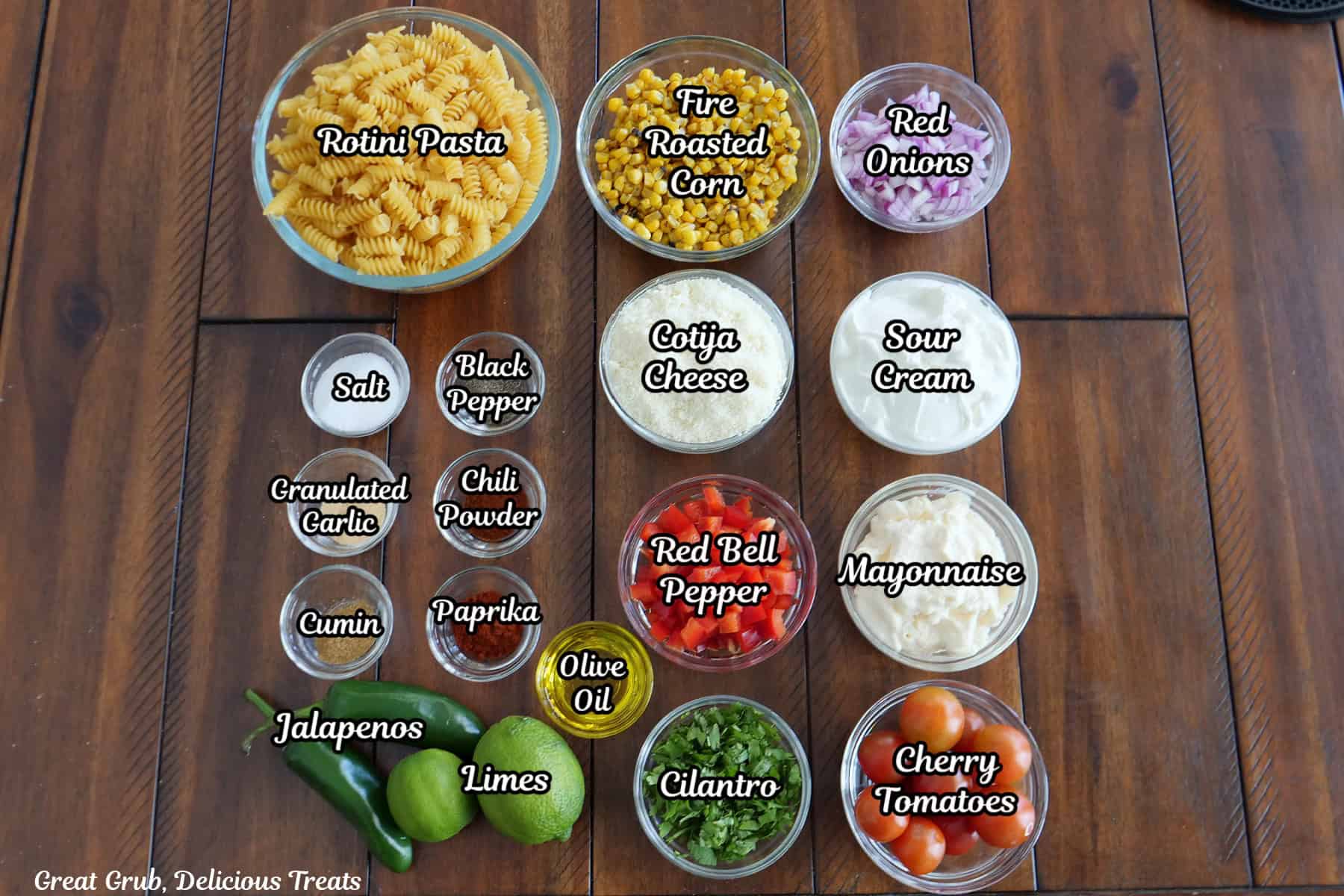A wood surface with all the ingredients placed on it to make street corn pasta salad.