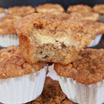 A stack of banana cream cheese muffins on top of each other with a bite taken out of the one on top, and a title overlay at the top.