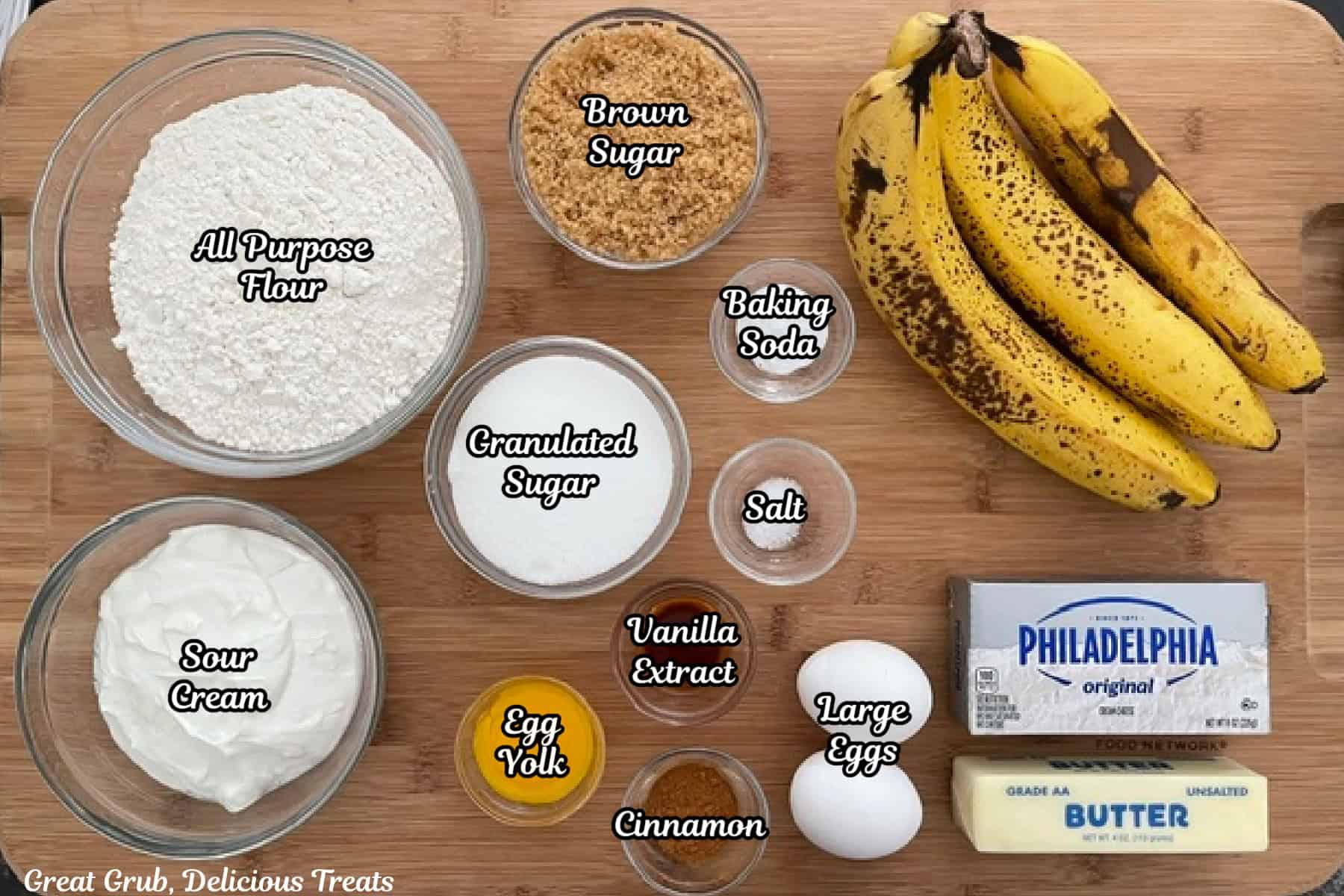 A wood surface with all the ingredients placed on it to make banana cream cheese muffins.