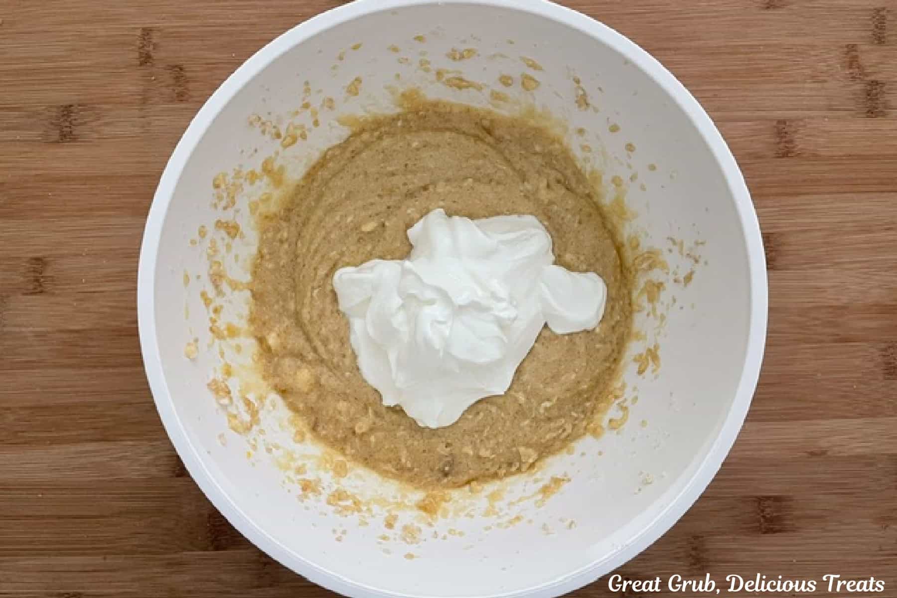 A wood surface with a mixing bowl with the wet banana muffin batter on it.