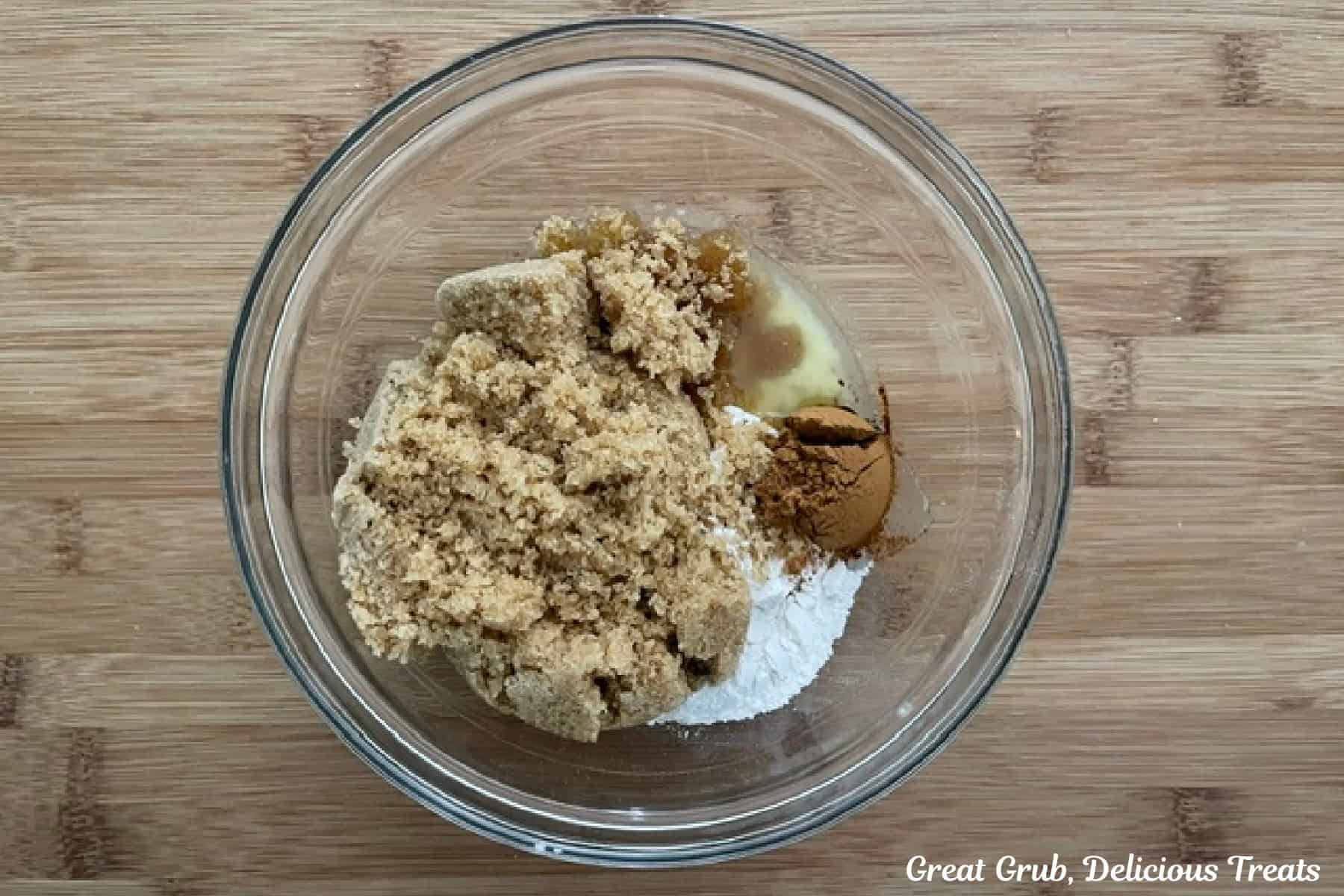 A wood surface with a glass bowl filled with all the streusel ingredients in it before being mixed together.