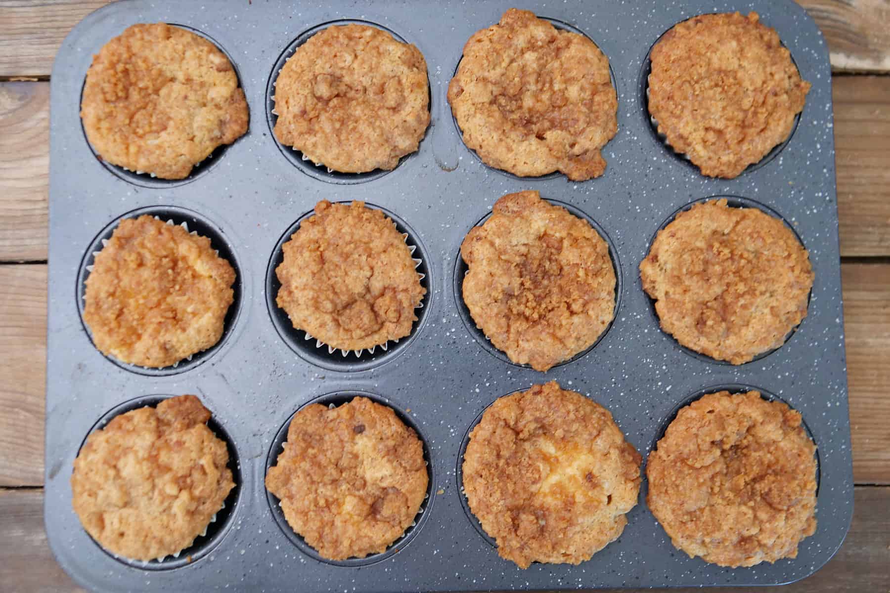 A 12-count muffin tin with baked banana cream cheese muffins in it.