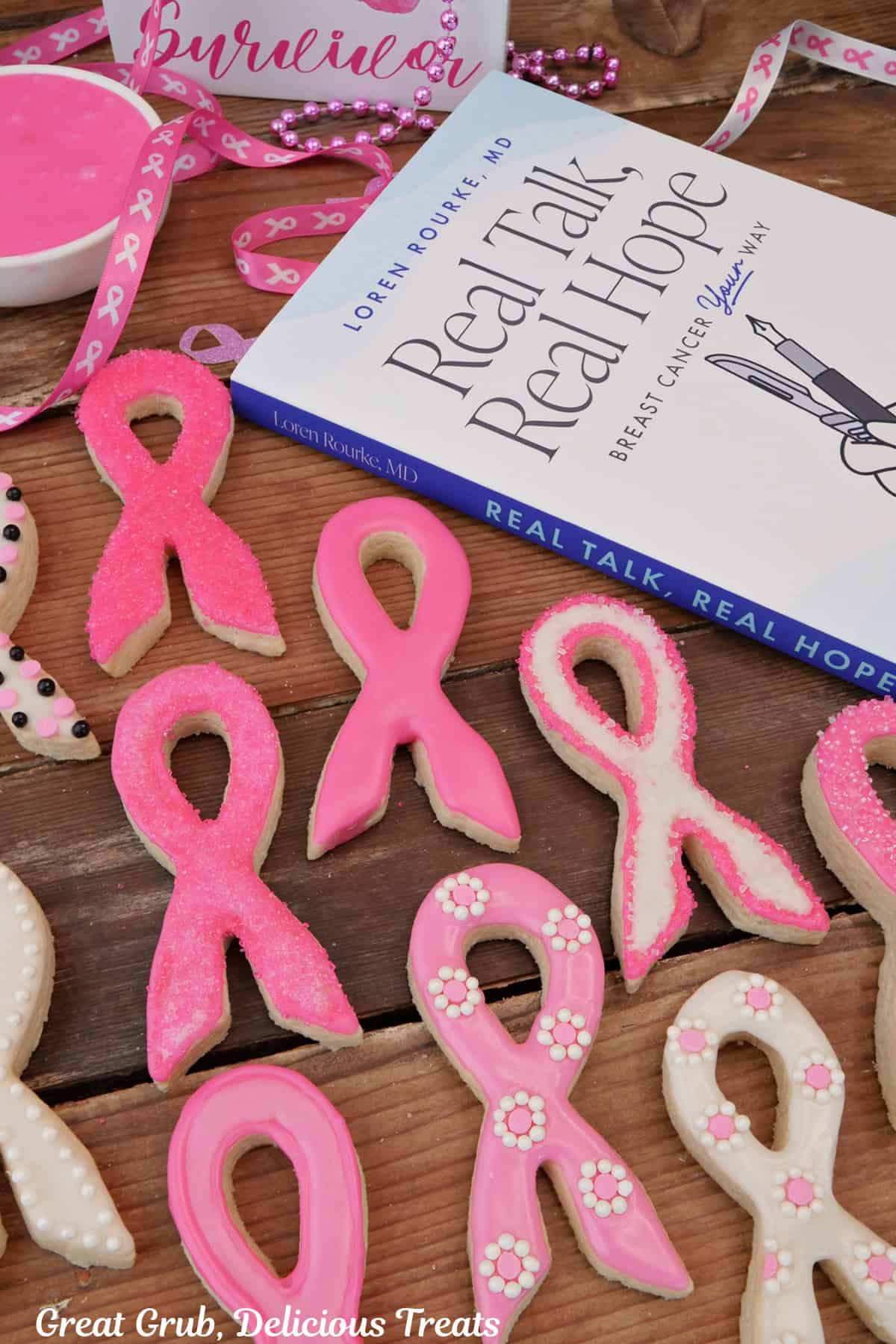 A wood surface with pink and white ribbon sugar cookies and Dr. Loren Rourke's book, Real Talk, Real Hope in the background.