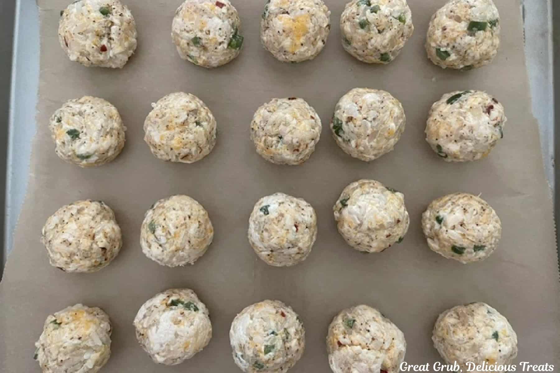 A baking sheet with twenty chicken rice bites on it.