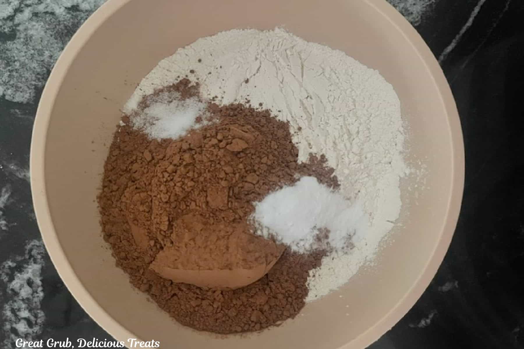 A cream colored bowl with the dry chocolate cake ingredients in it.