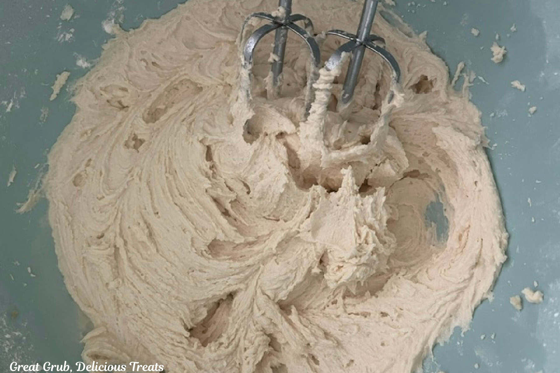A light blue bowl with the salted caramel frosting being mixed together.