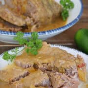 Two what plates with blue trim with crockpot spicy queso roast beef on them, and a title overlay at the top.
