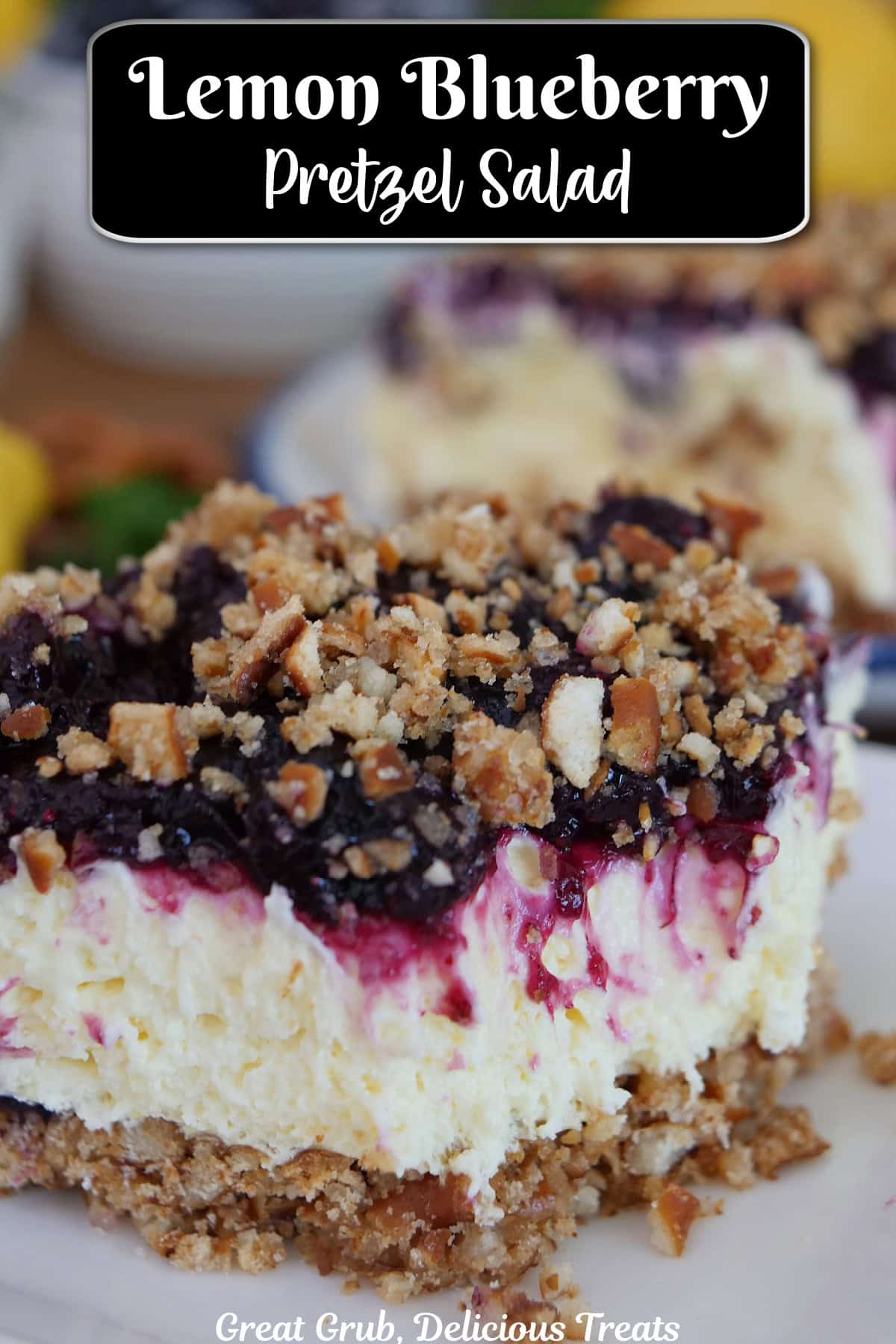 A white plate with a serving of lemon blueberry pretzel salad on it with a bite taken out of it, and a title overlay at the top.
