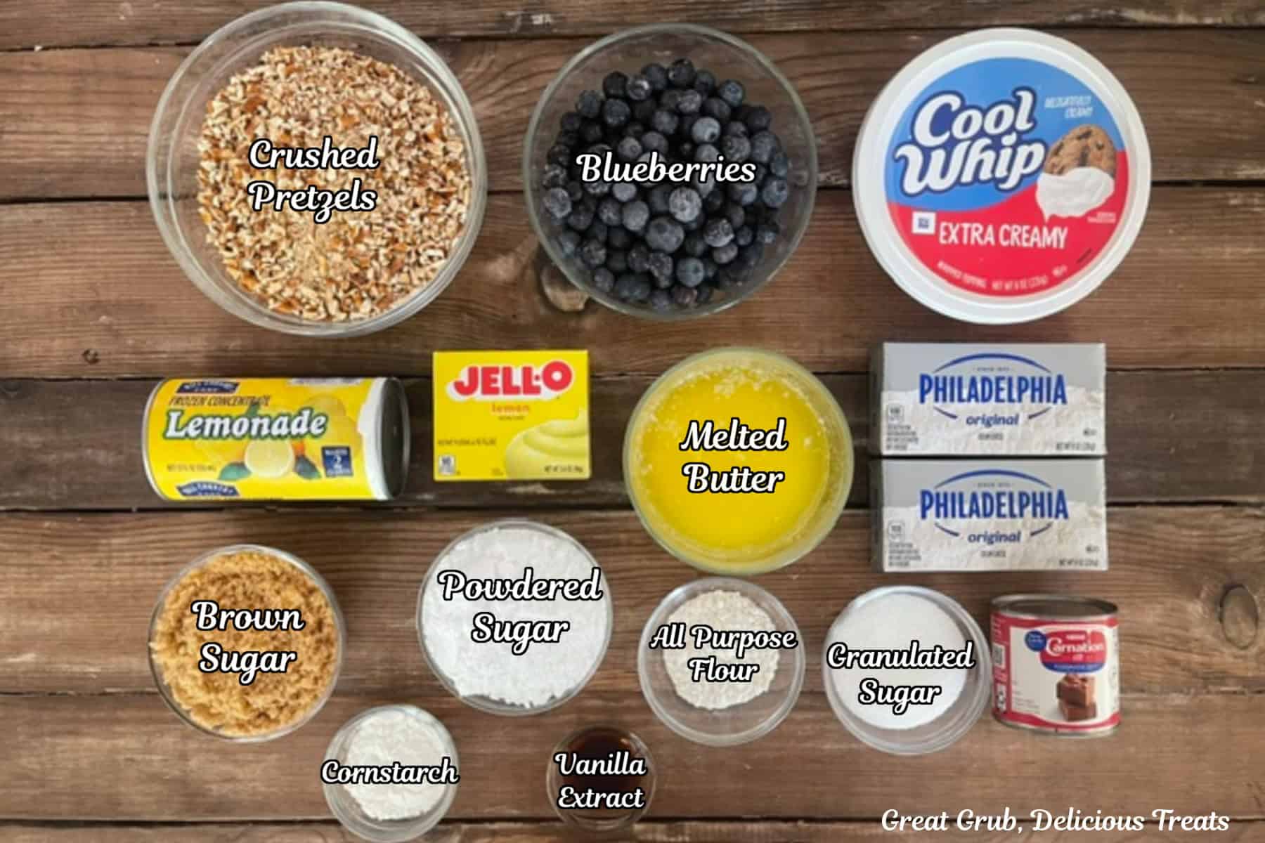 A wood surface with all the ingredients placed on it to make lemon blueberry pretzel salad.