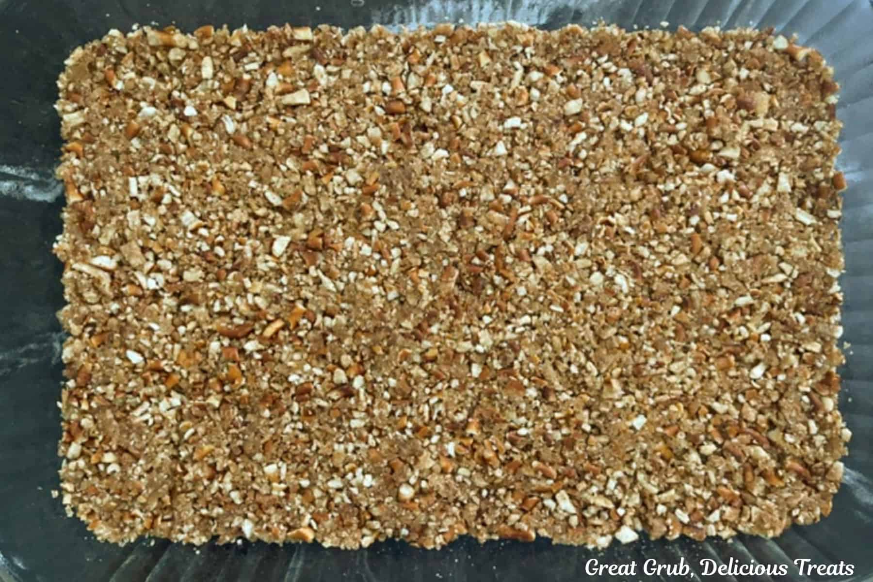A glass 9 by 13 glass baking dish with a pretzel crust in it.