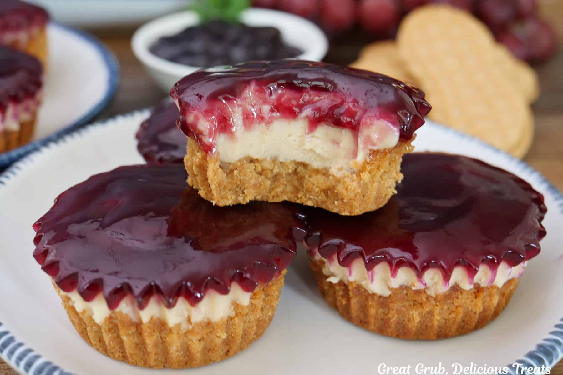 A round with plate with blue trim with four mini peanut butter and jelly cheesecakes on it with a bite taken out of the cheesecake on top.