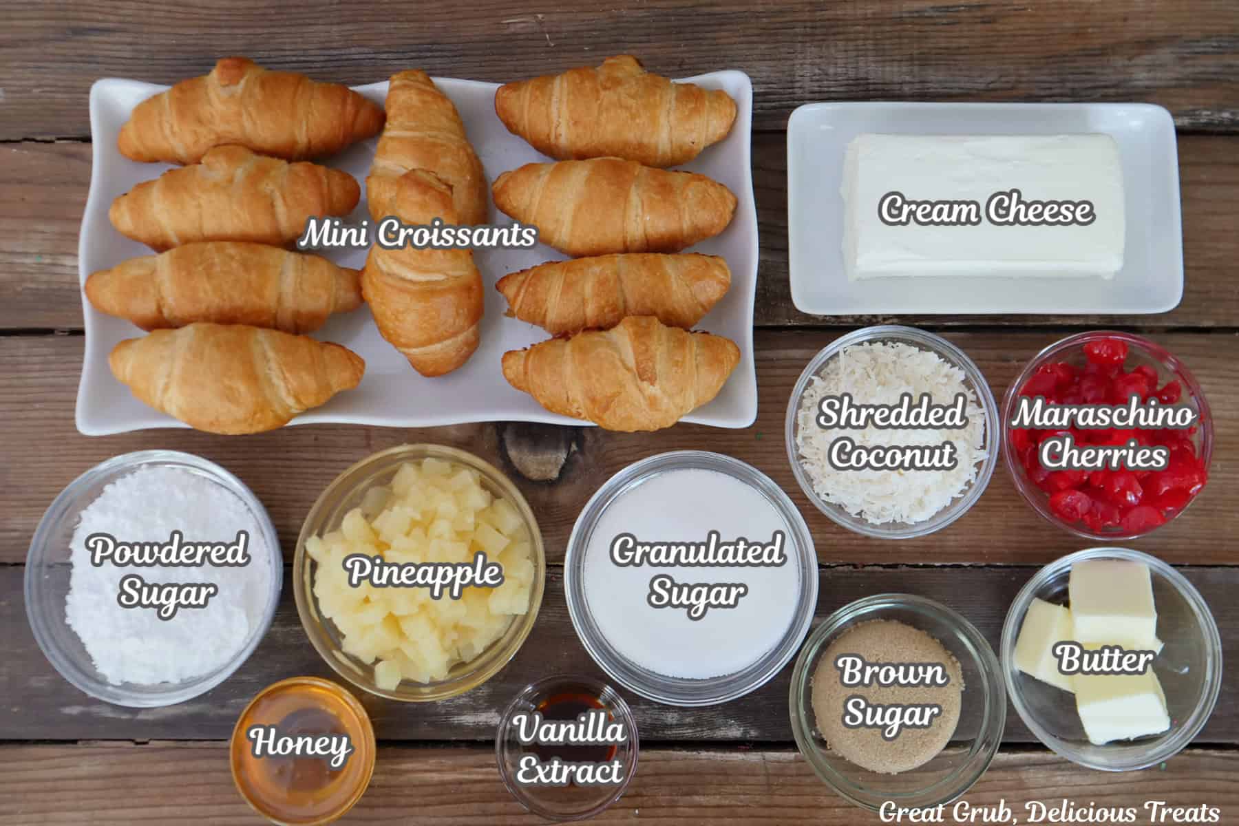 A rustic wood surface with all the ingredients placed on it to make mini pineapple cherry cheesecake croissants.