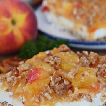 A white plate with a slice of peach pretzel dessert on it with a bite taken out, and another slice and a peach in the background, and a title overlay at the top.