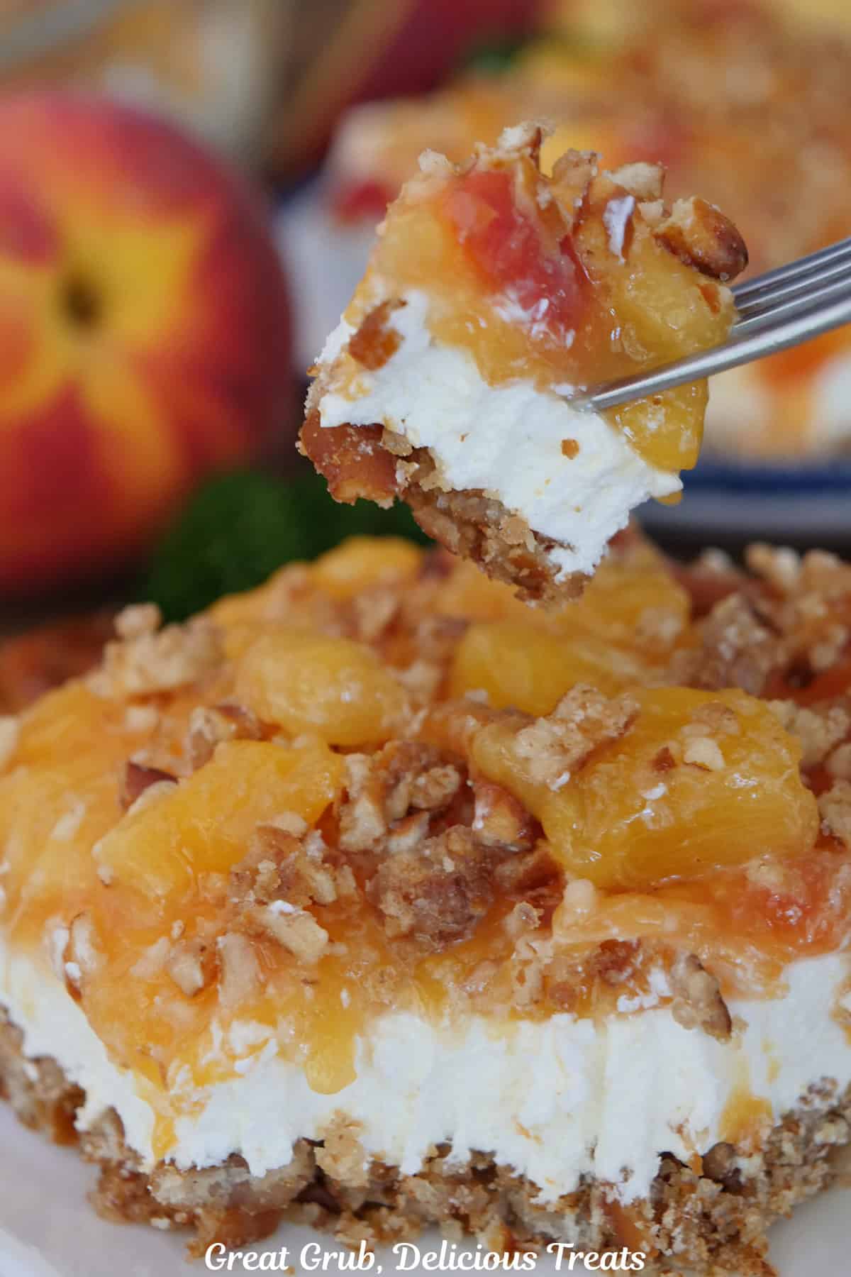 A bite of peach pretzel dessert on a fork held above a serving of the dessert on a plate below.