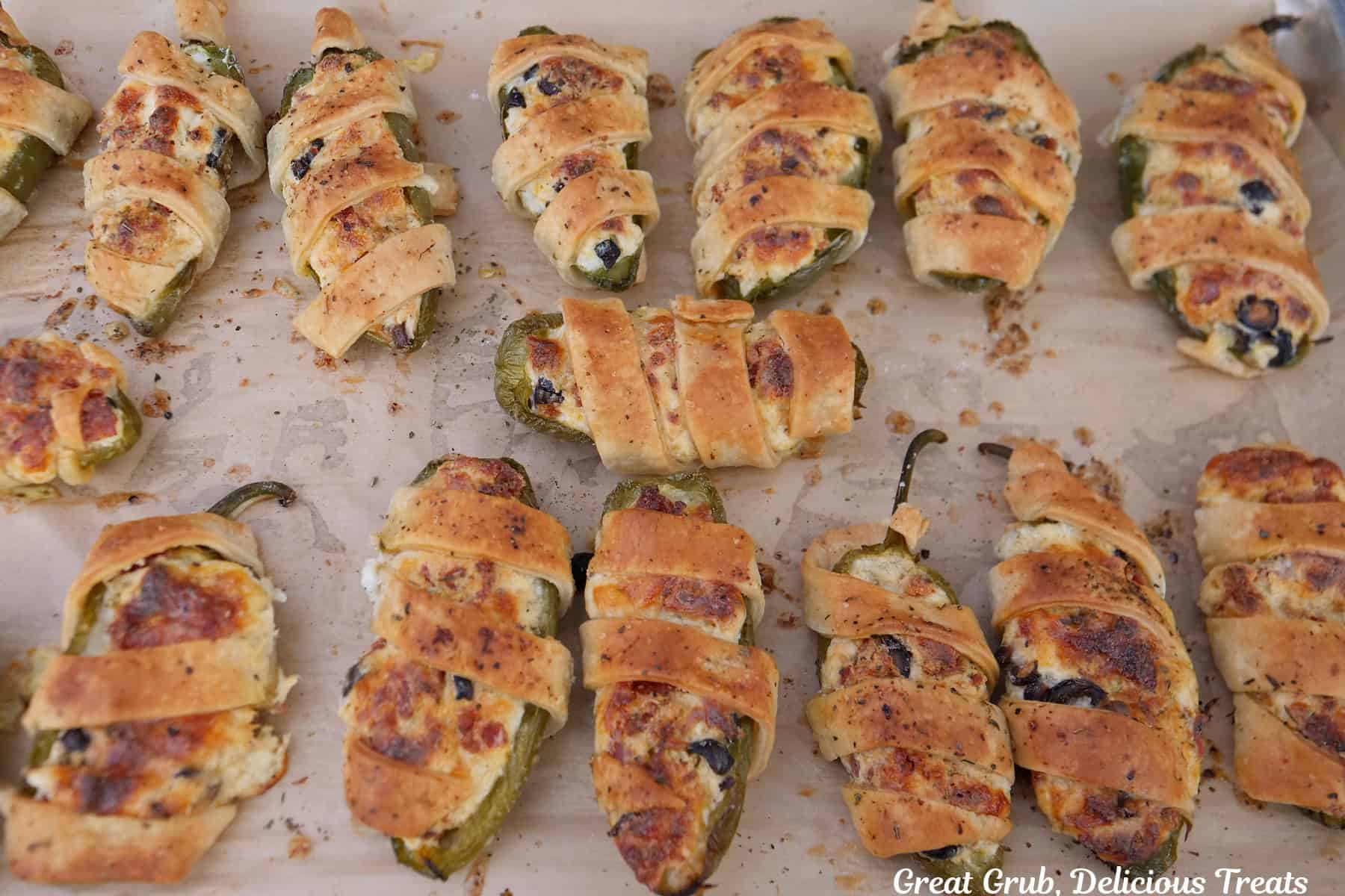 A parchment paper lined baking sheet with baked pepperoni pizza jalapeno poppers on it.