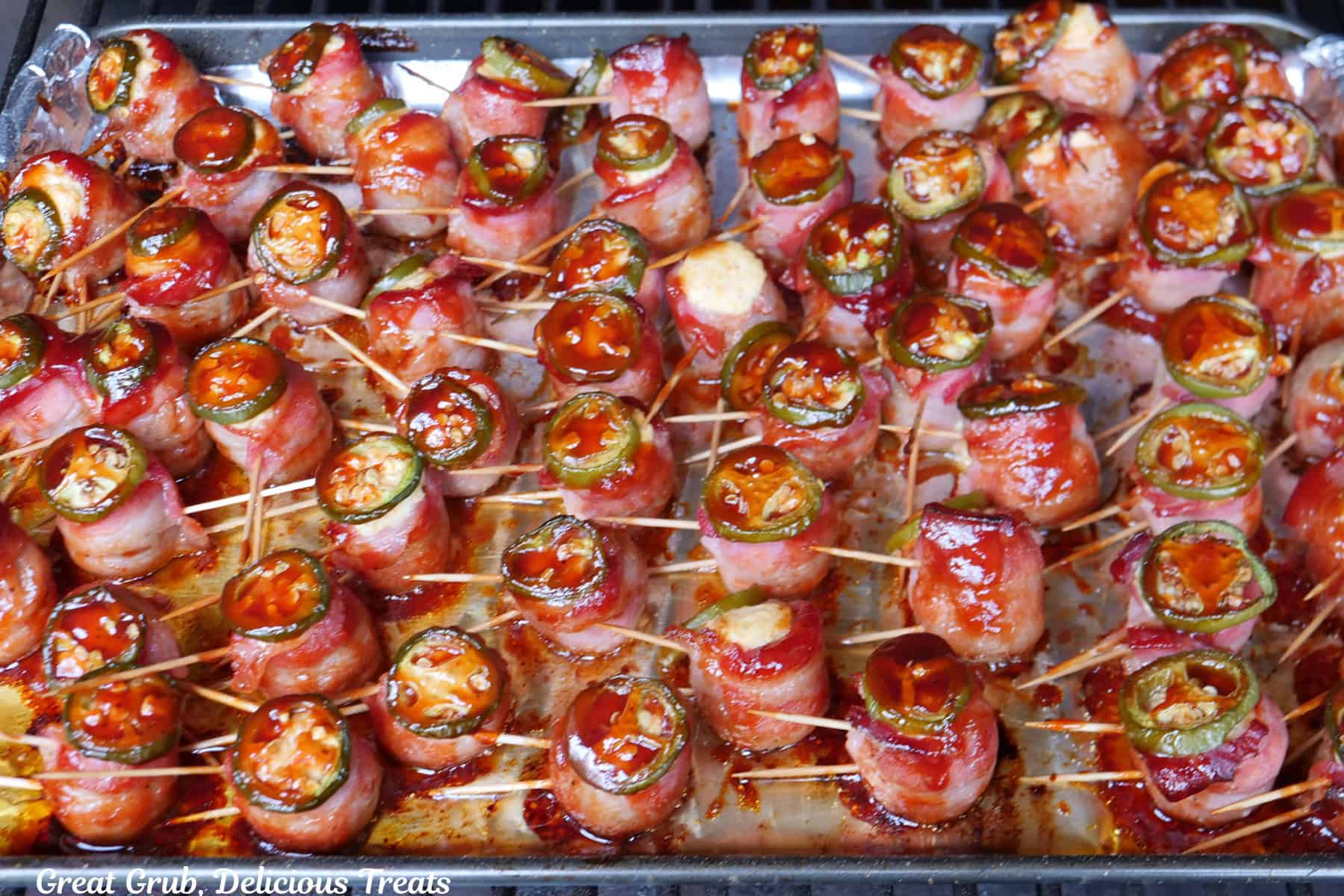 The meatball pig shots on a baking sheet lined with foil as they are beginning to cook on the smoker.