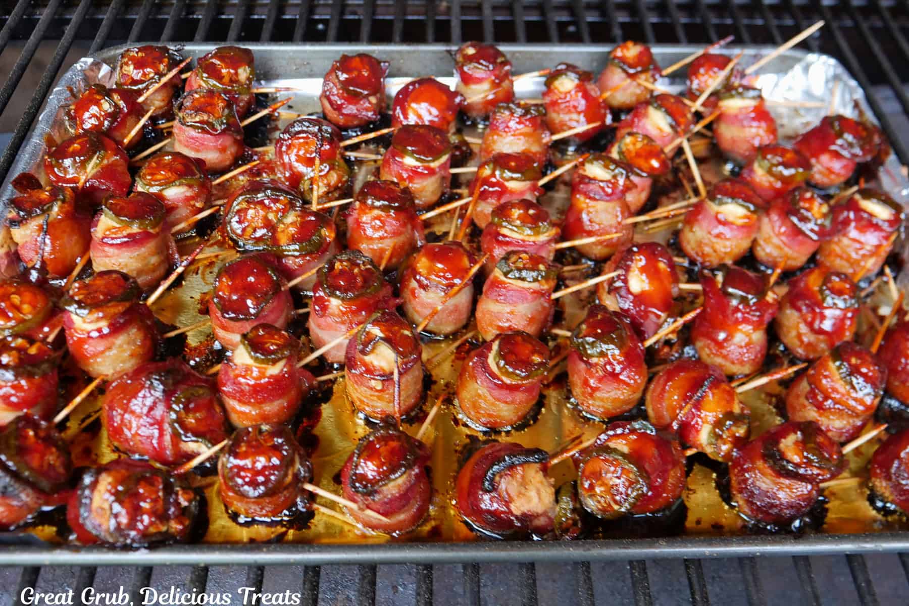Meatball pig shots on a baking sheet lined with aluminum foil, and are brushed again with BBQ sauce and continuing to cook on the smoker.