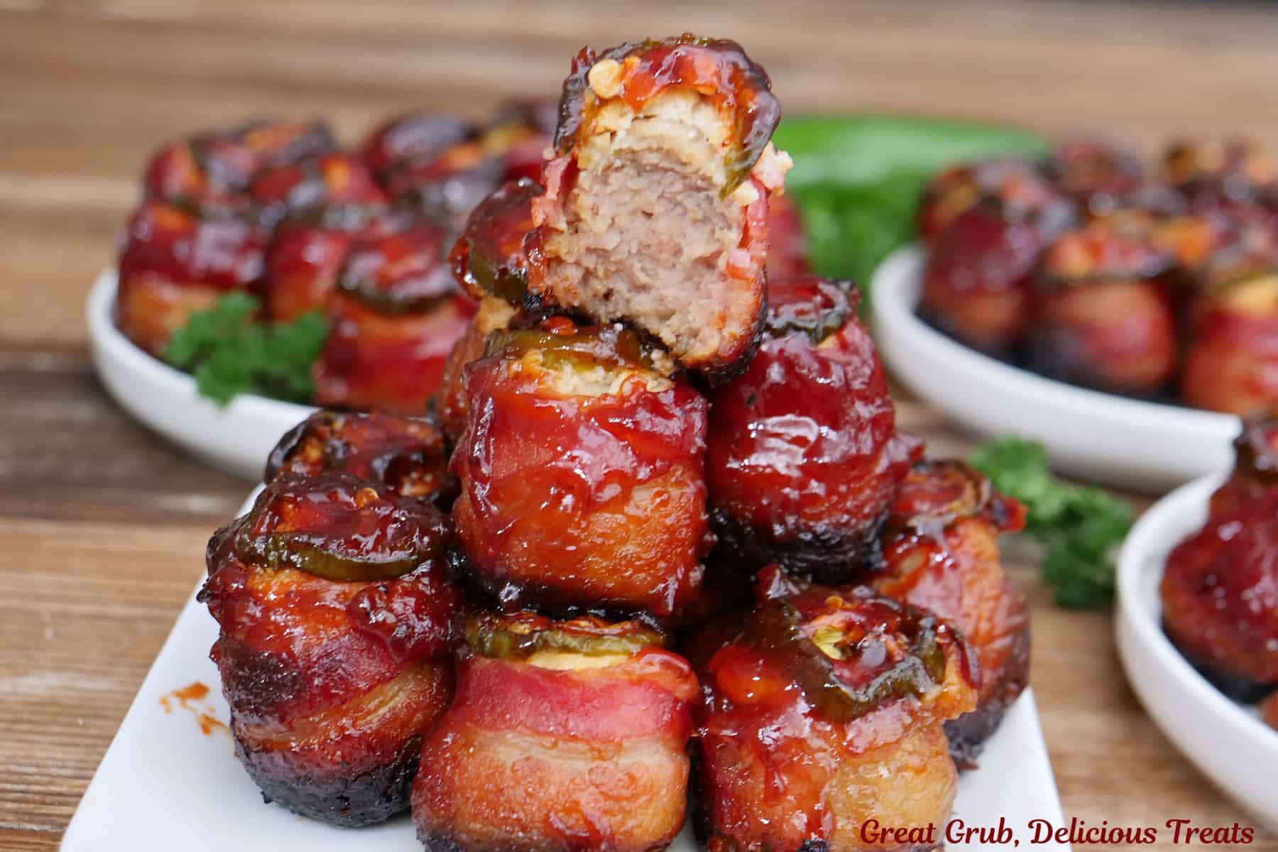 A white square plate with a stack of smoked meatball pig shots on it with a bite taken out of the one on top.