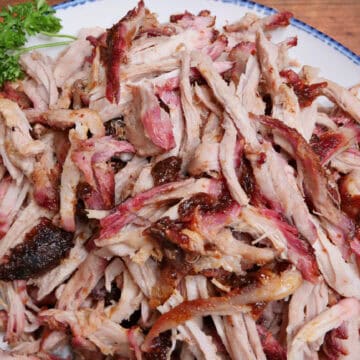 A white plate with blue trim with shredded smoked pork roast on it and a title overlay at the top.