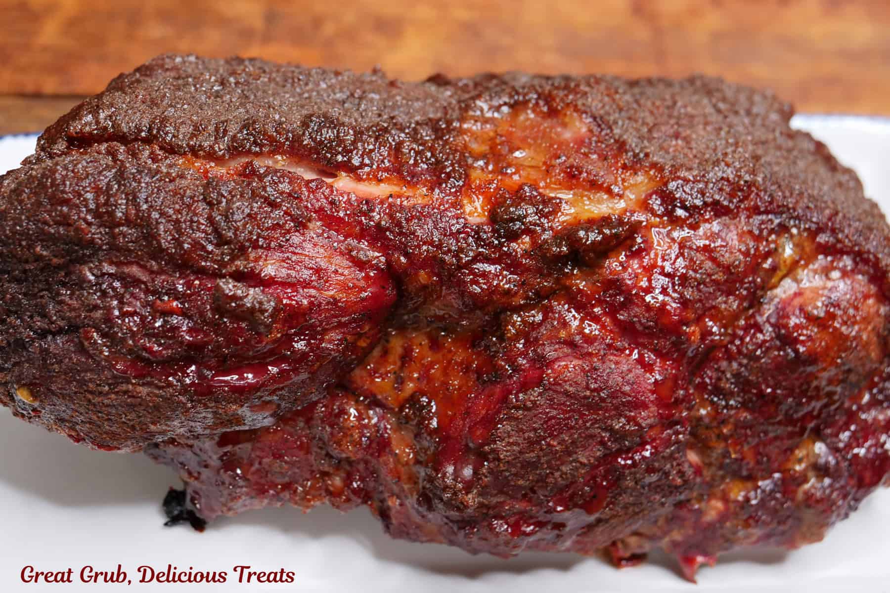 A smoked pork roast placed on a white oblong plate with blue trim.