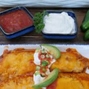 A white plate with blue trim with two shredded beef enchiladas on it with a title overlay at the top.