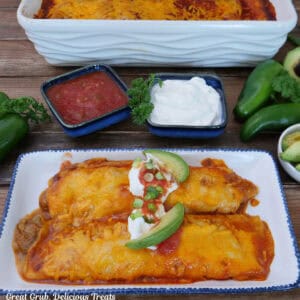 A white oblong plate with two spicy queso shredded beef enchiladas on it.