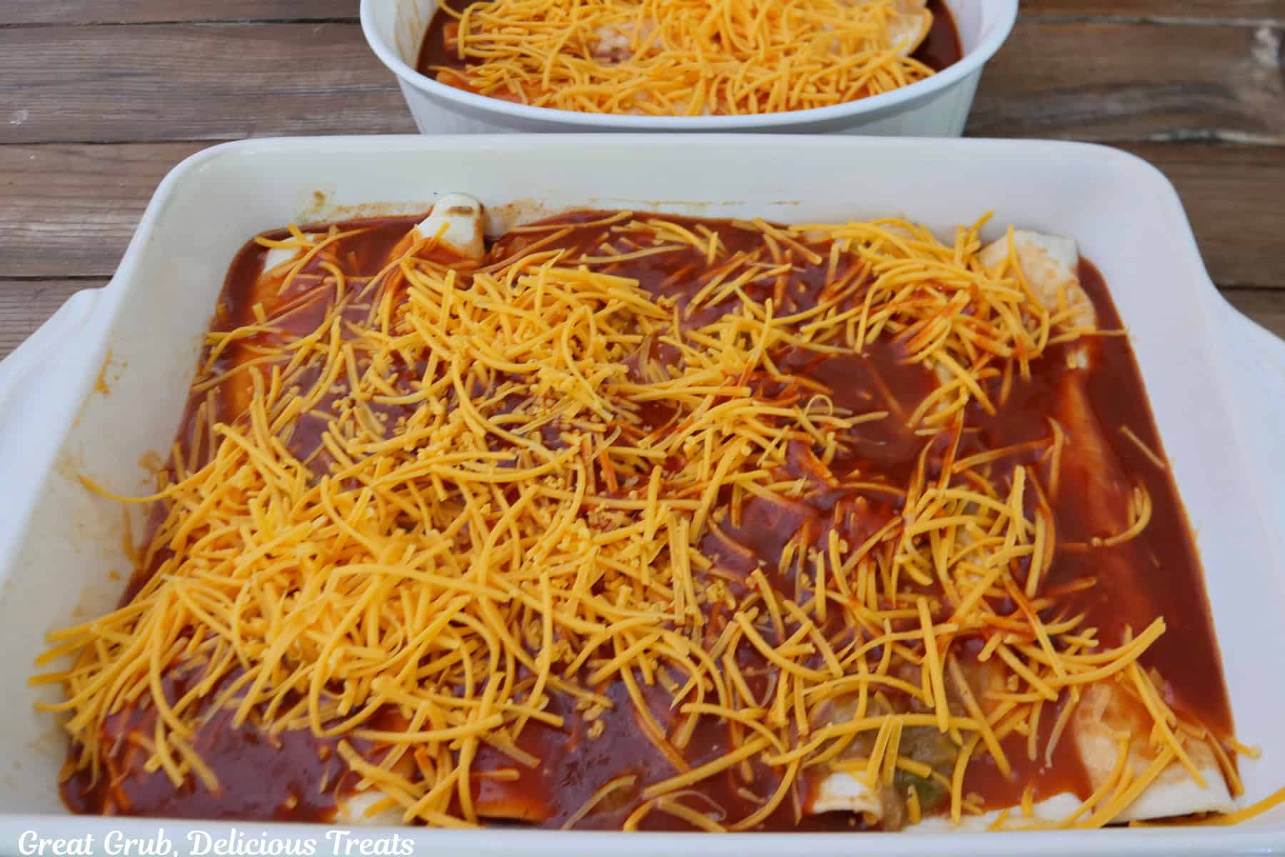 A white baking dish with spicy queso shredded beef enchiladas in it before going into the oven.