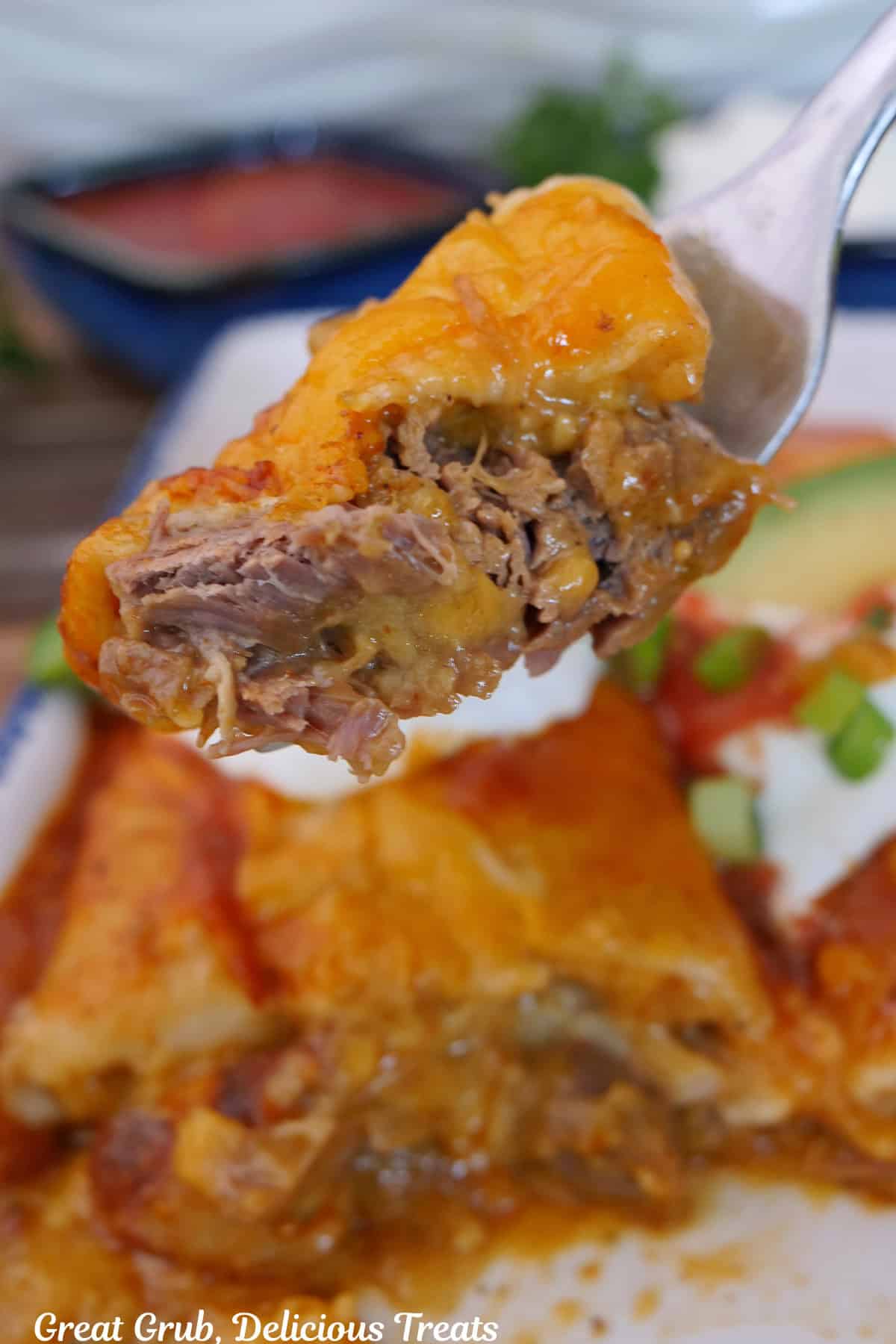 A bite of spicy queso shredded beef enchiladas on a fork.