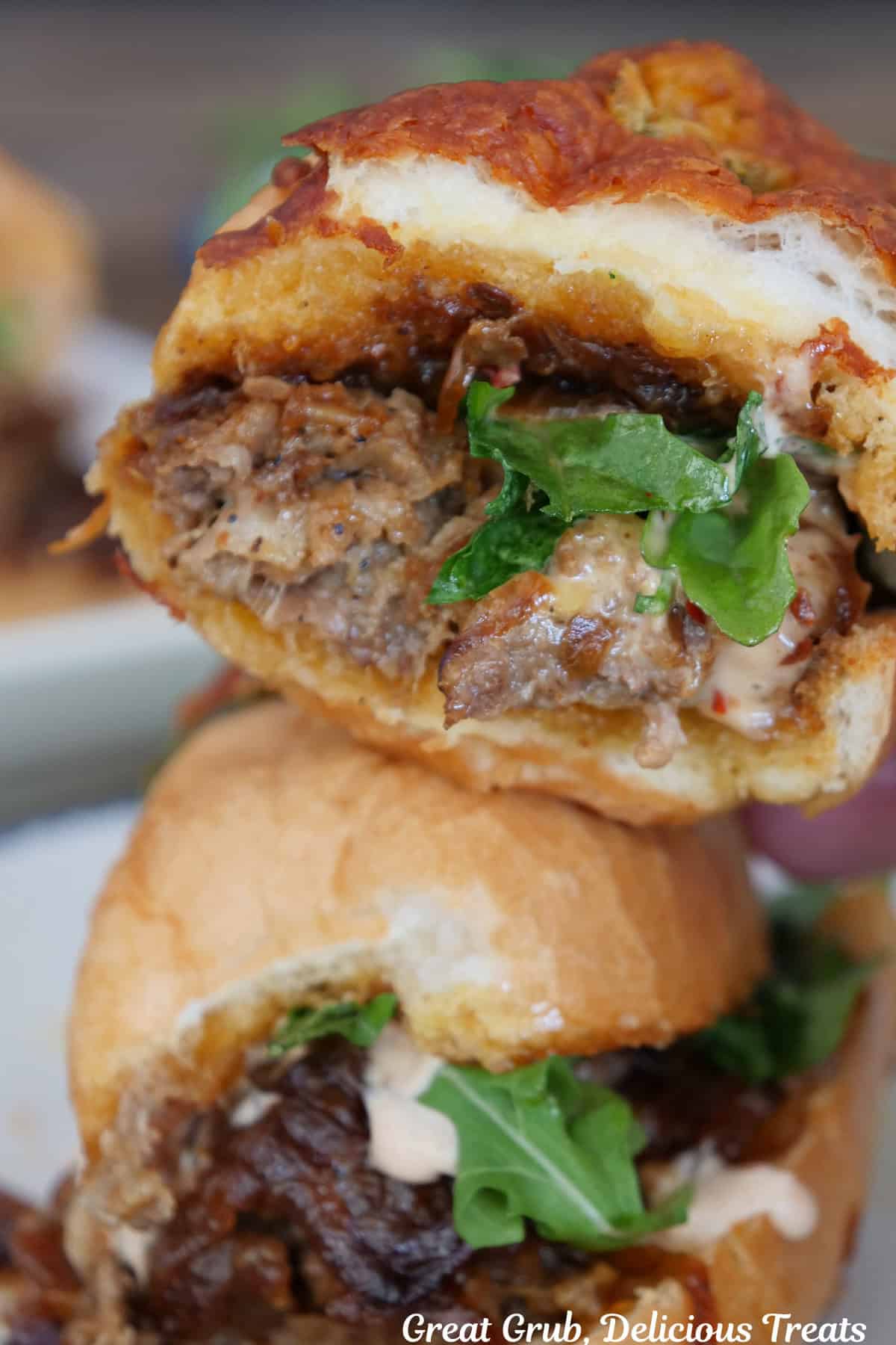 Two halves of a steak sandwich stacked on top of each other with a few bites taken out of the one on top.