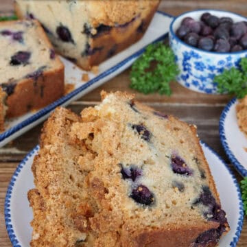A round white plate with blue trim with two slices of blueberry cream cheese loaf on it with a title overlay at the top.