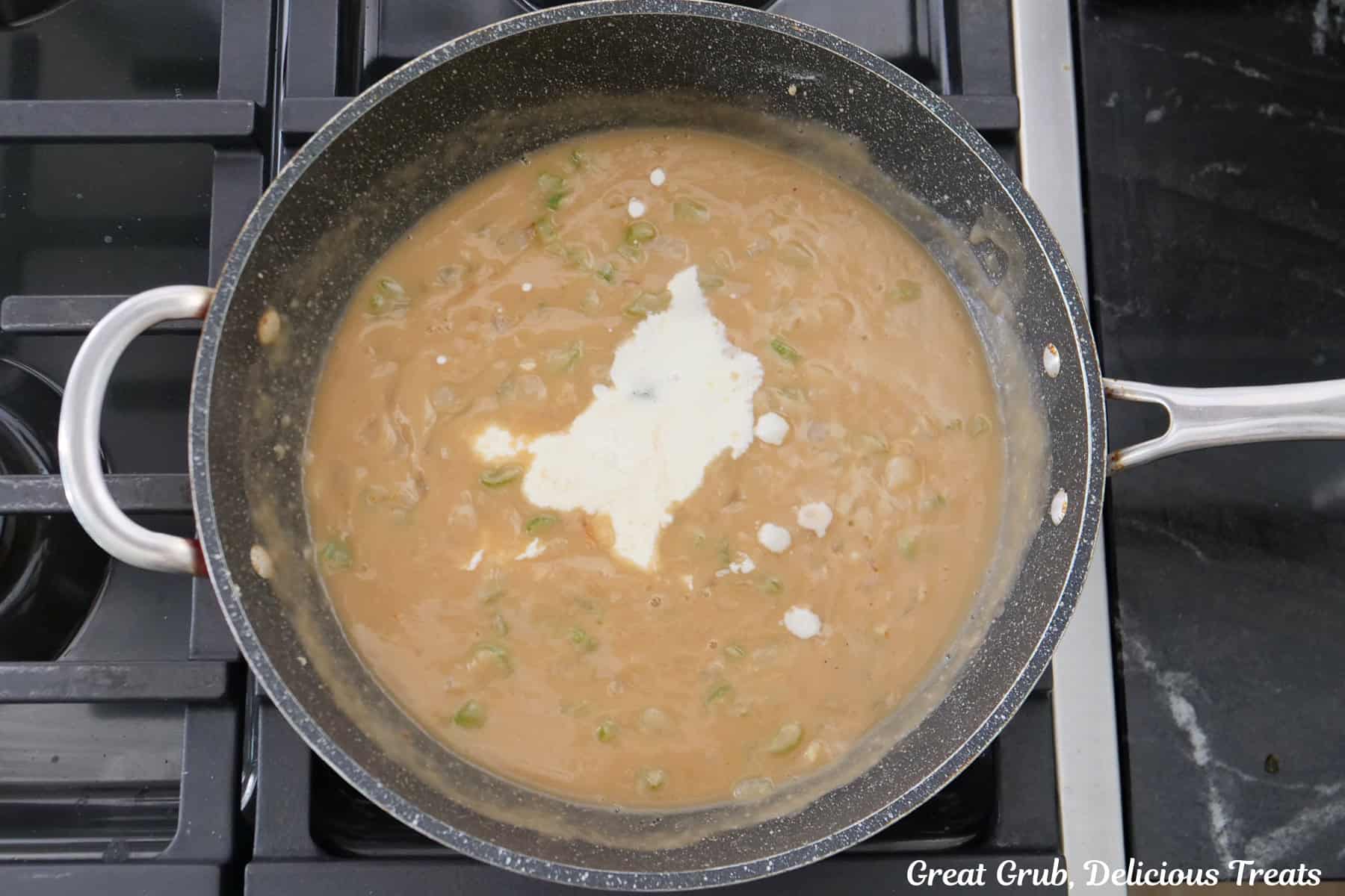 A frying pan on the stove with a rich and creamy beef sauce with heavy cream added.