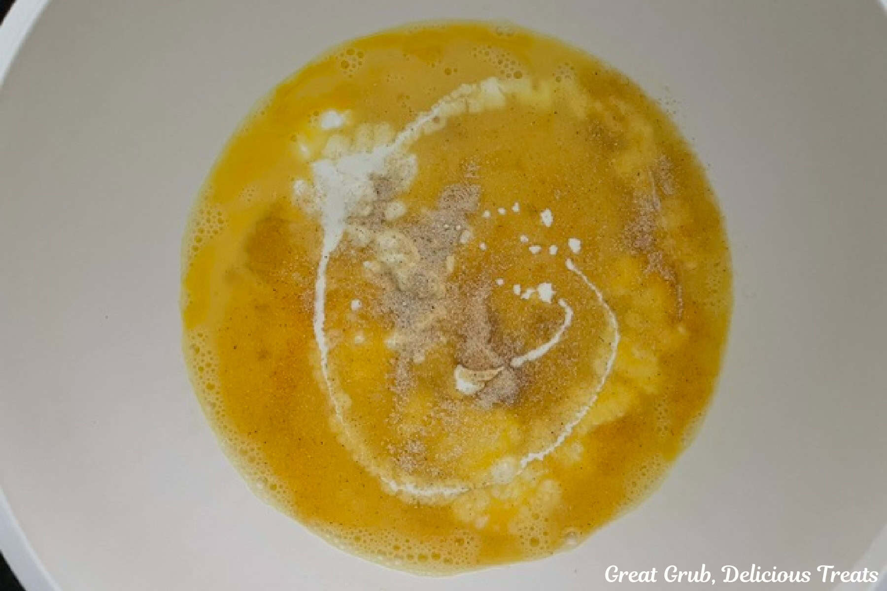A white bowl filled with the egg mixture before it is all mixture together.