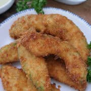 A round white plate with blue trim with six crispy avocado fries on it, and a title overlay at the top.