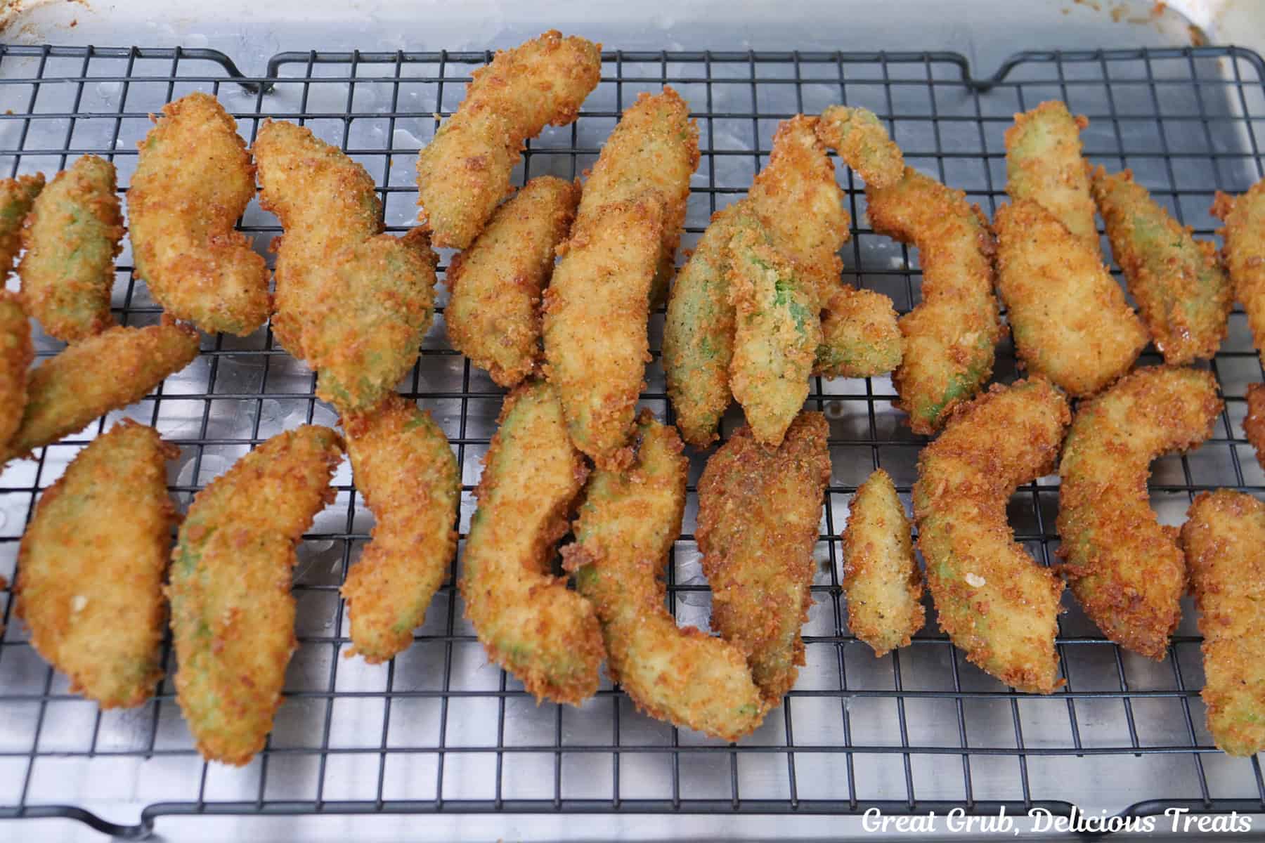 A wire rack with fried crispy avocado fries on it.