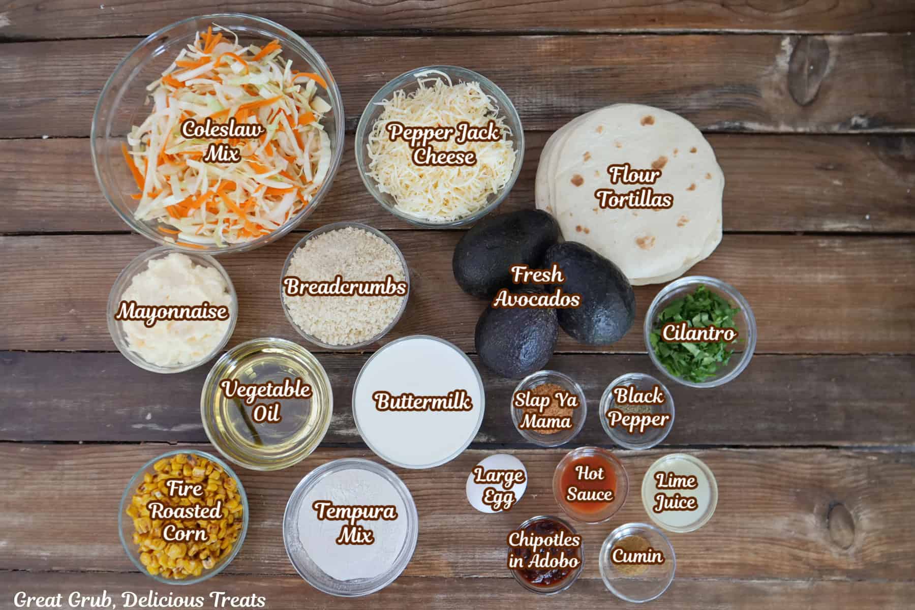 A woos surface with all the ingredients placed on it to make crispy avocado tacos with southwest corn slaw.