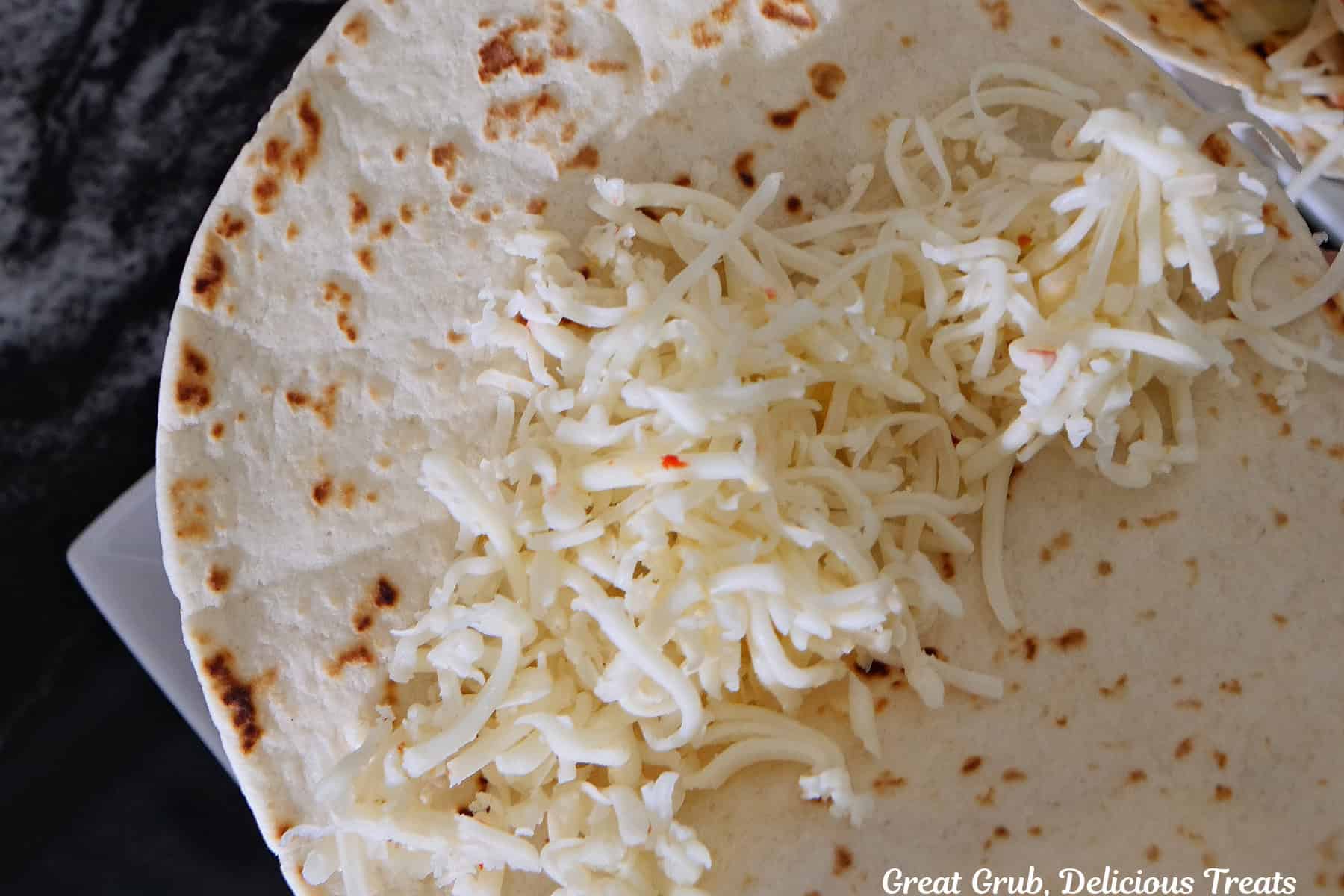 A flour tortilla with shredded pepper jack cheese in the center.