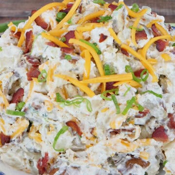 A rustic wood surface with a big bowl of loaded baked potato salad in it with a title overlay at the top.