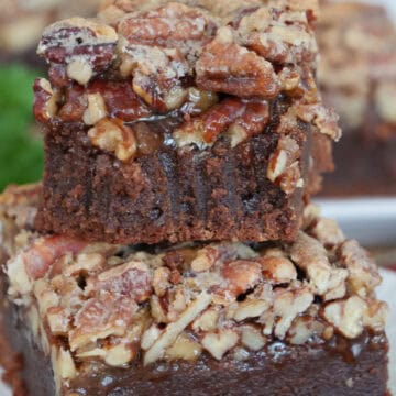 Two pecan pie brownies on a white plate stacked on top of each other with a bite taken out of the one on top, and a title overlay at the top.