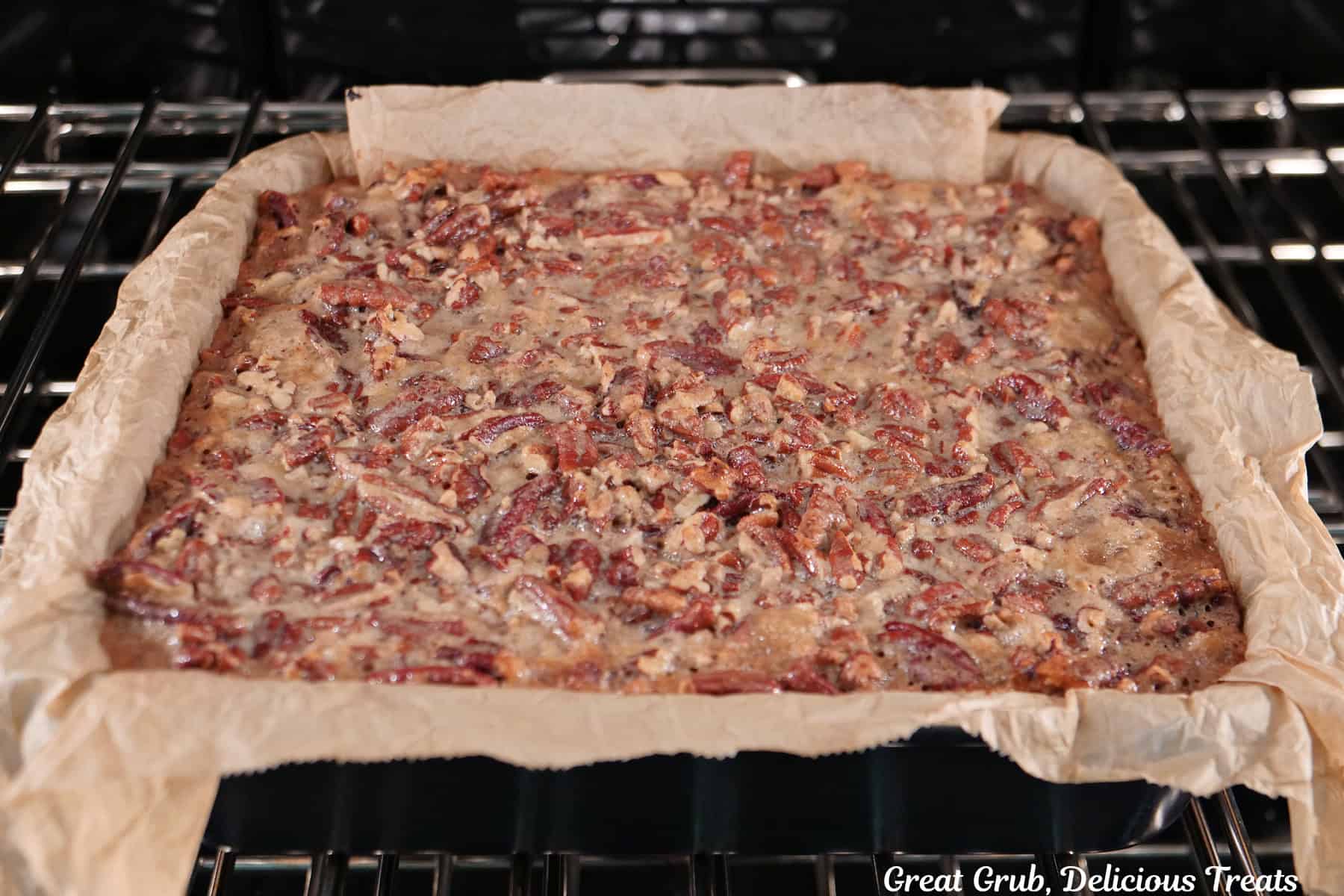 A 9 by 9 baking dish with the pecan pie brownies in the oven baking.