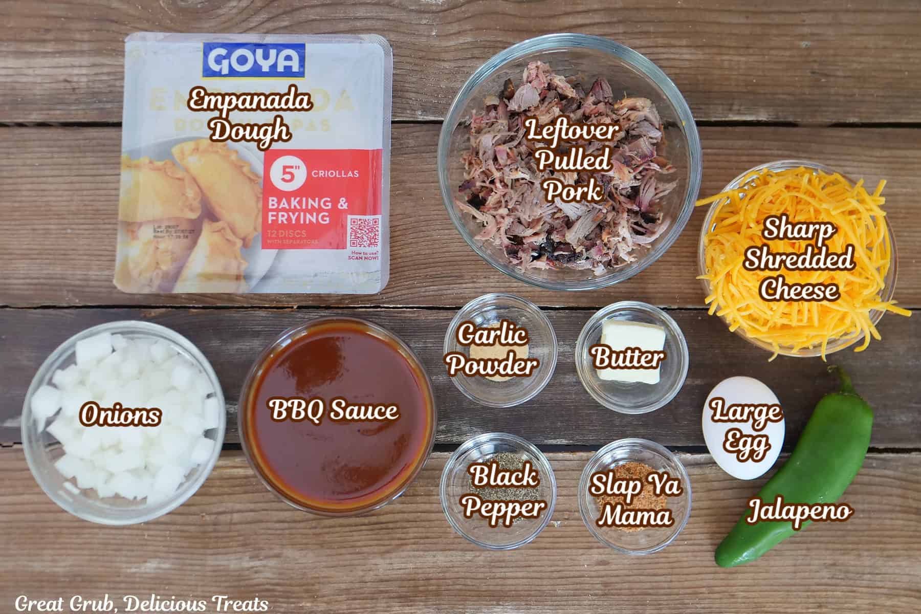 A rustic wood surface with all the ingredients placed on it to make pulled pork empanadas.